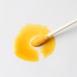 Biodegradable cotton buds bulk pack on a white background with a yellow liquid stain