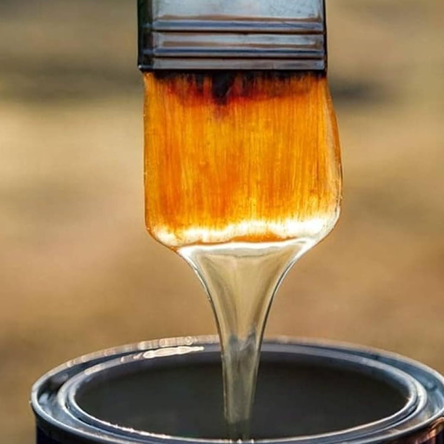 Brush dipping into a tin of clear gloss varnish paint, showcasing its smooth texture and finish