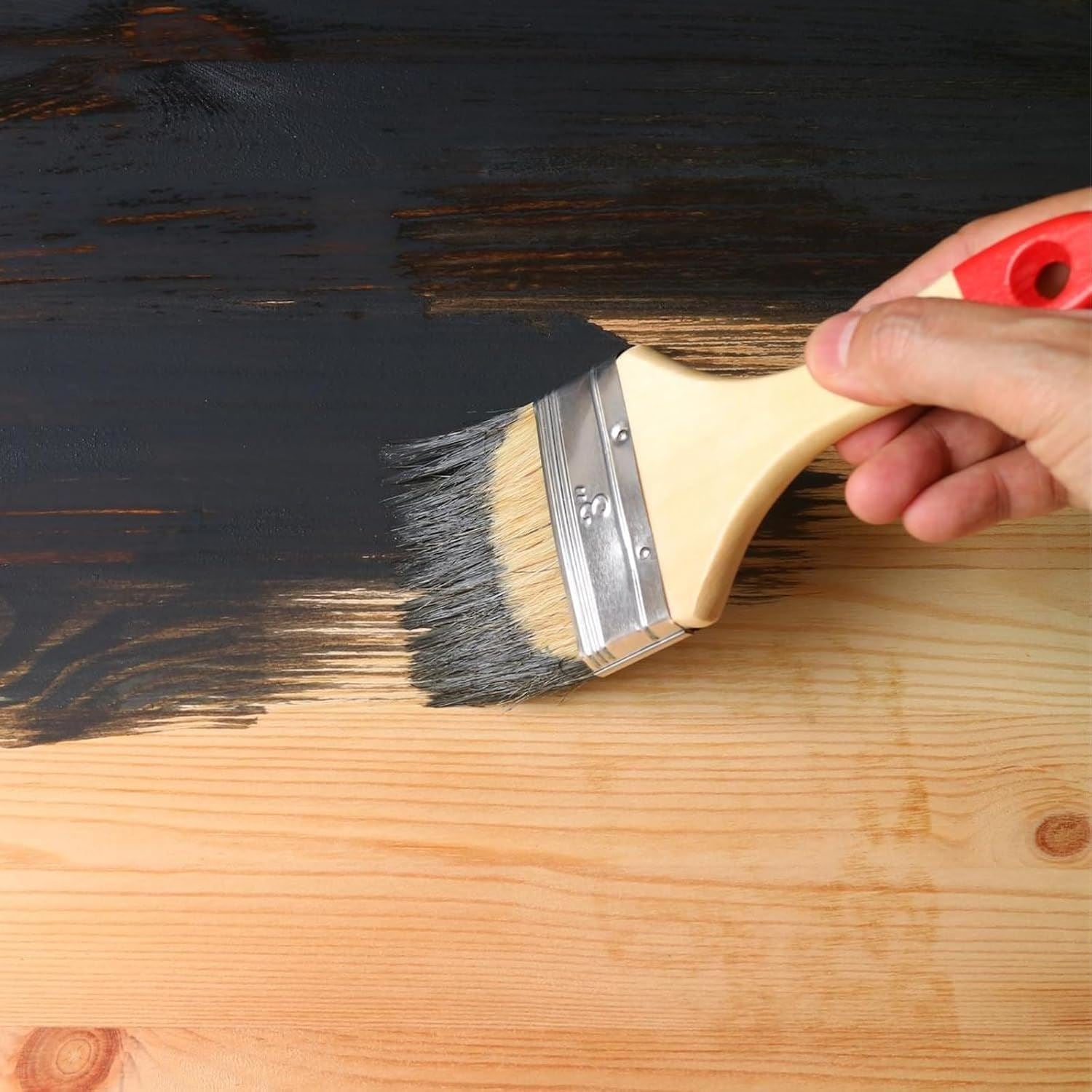 Applying black matt tin paint 300ml on wood surface with a brush for a smooth finish