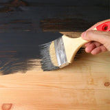 Applying black matt tin paint 300ml on wood surface with a brush for a smooth finish