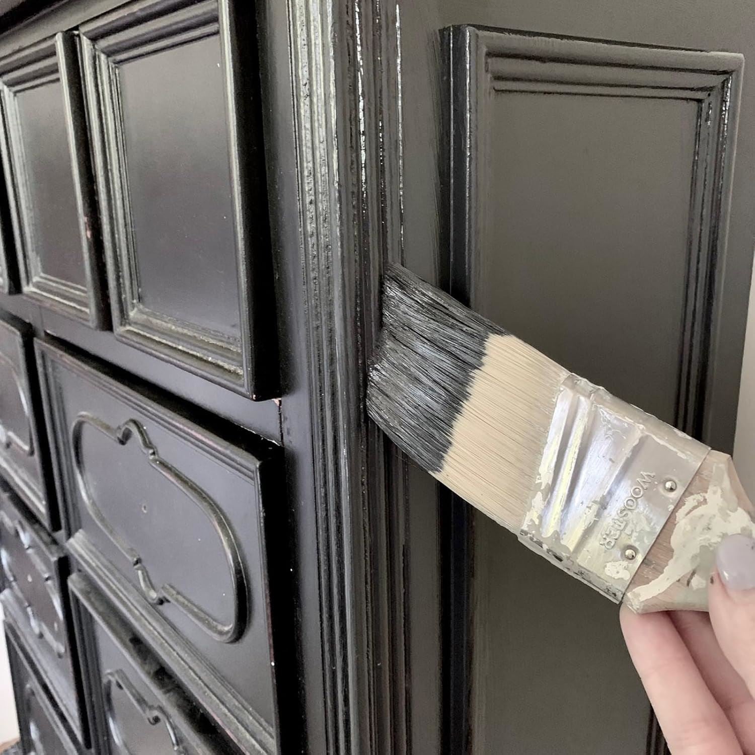 Nonslip black paint tin being applied to a wooden door with a paintbrush for a smooth finish