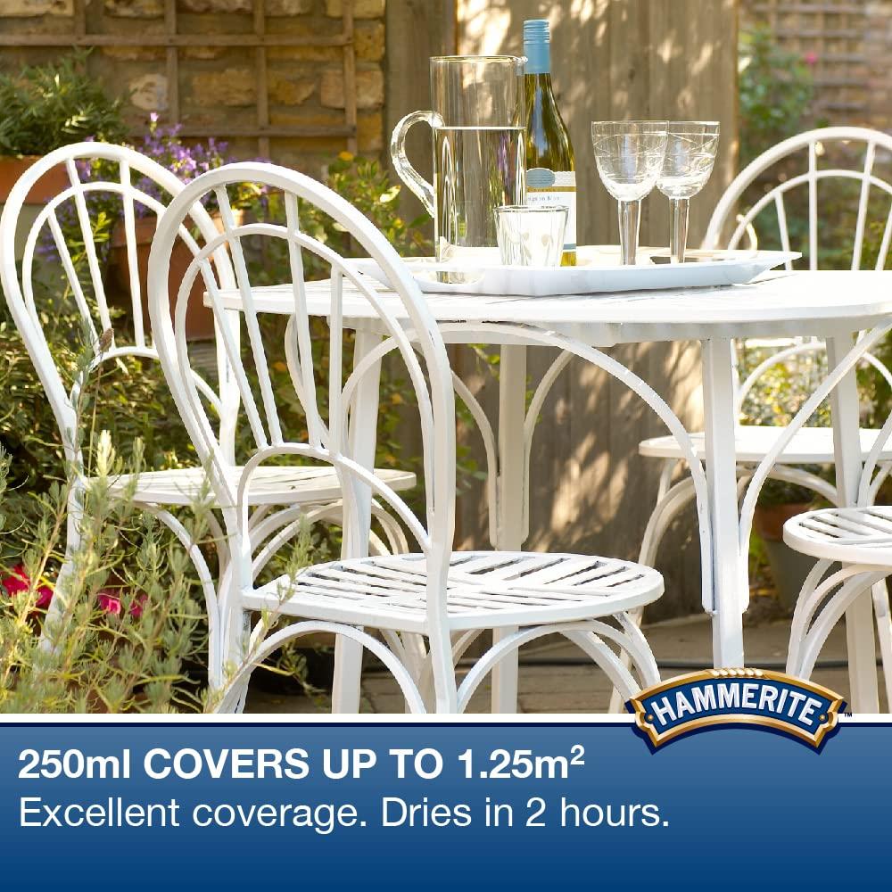 Hammerite smooth white paint 250ml displayed on a white garden table with chairs in a floral setting