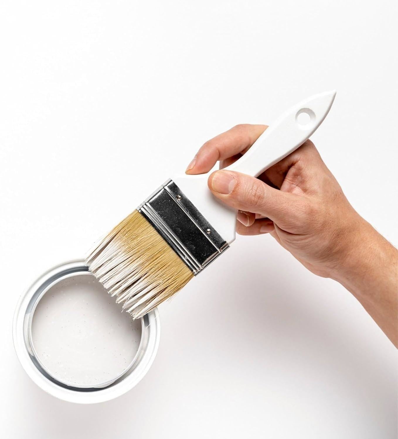 Hand holding a brush over a white matt tin paint 300ml can, ideal for home decorating