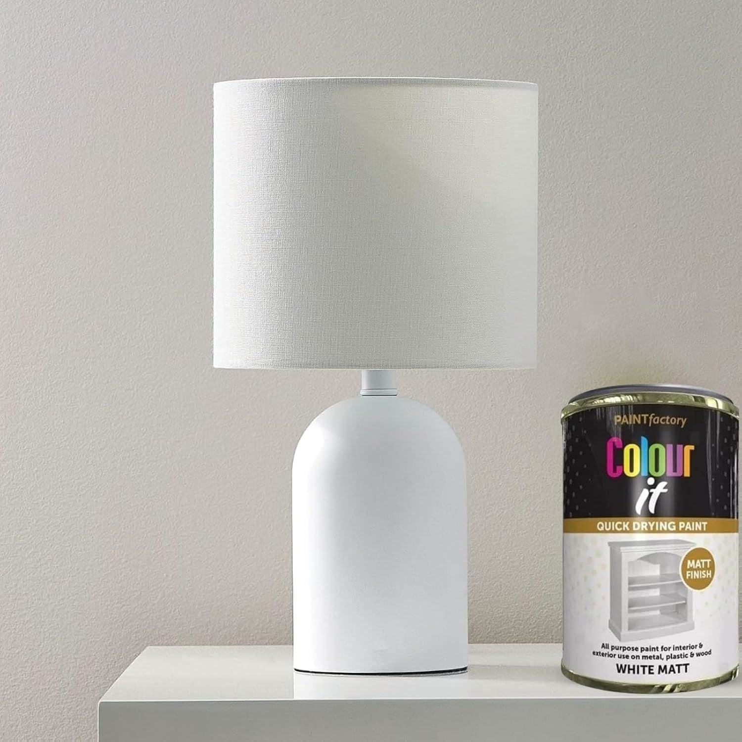 300ml white matt tin paint by Paint Factory beside a stylish white lamp on a table